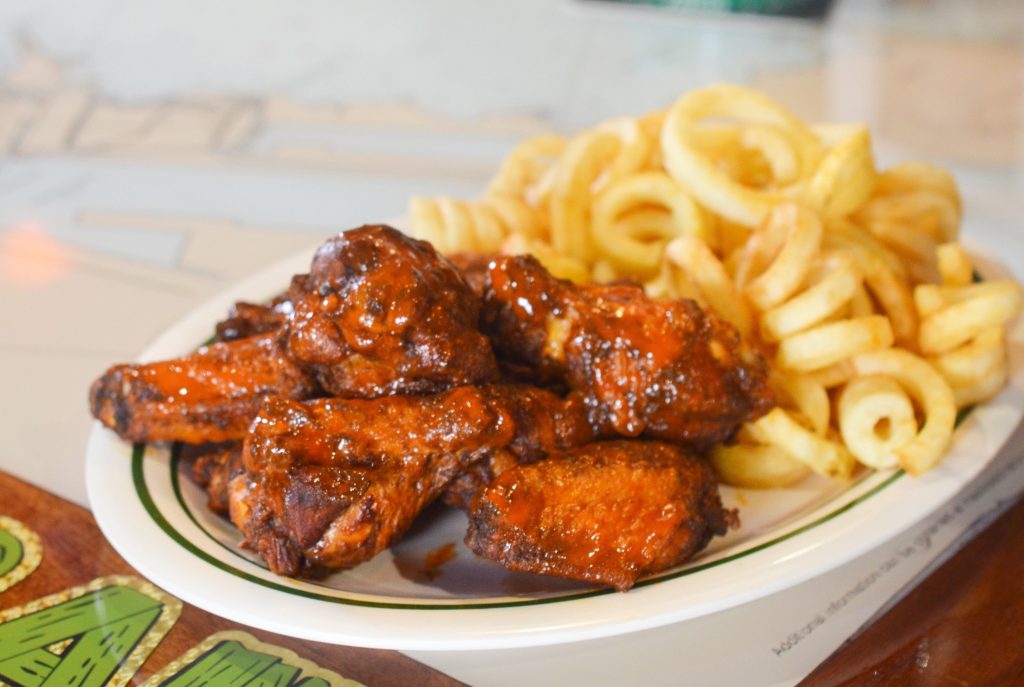 a plate of chicken wings with a side of curly fries