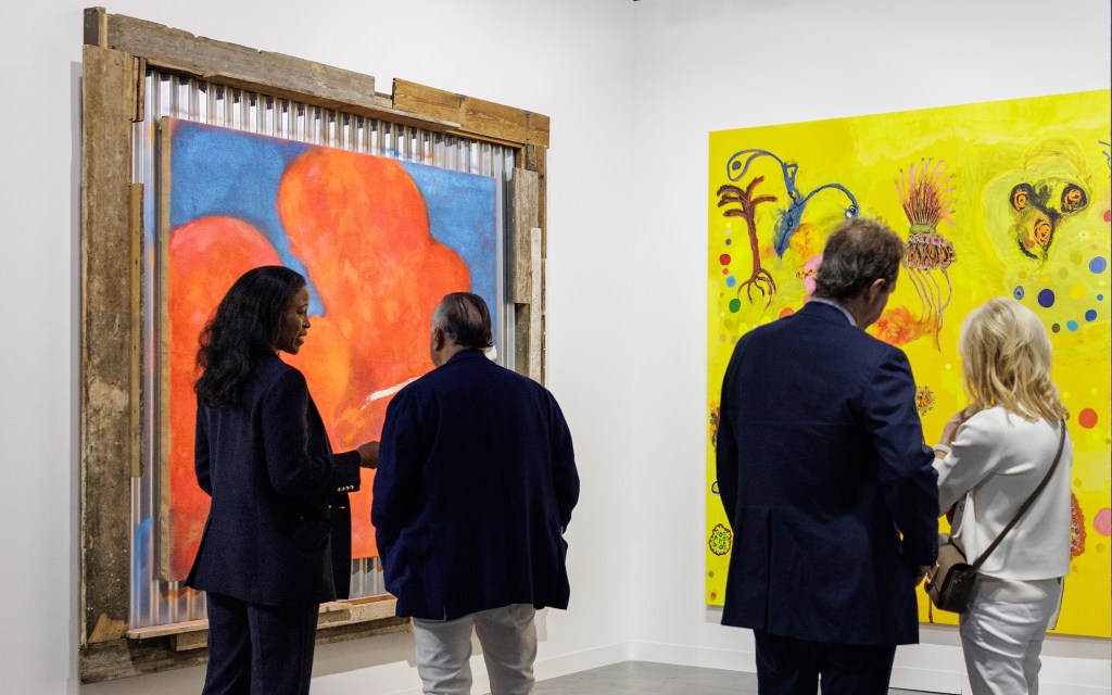 four people stand in front of two canvasses at an art gallery
