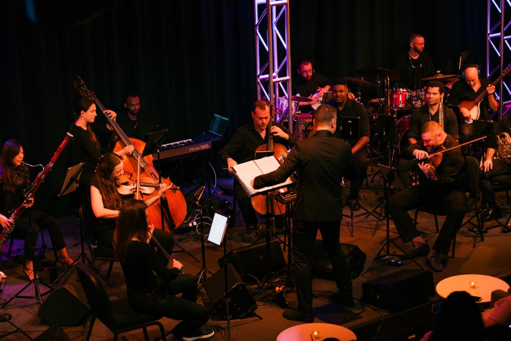 a conductor and orchestra perform on a stage