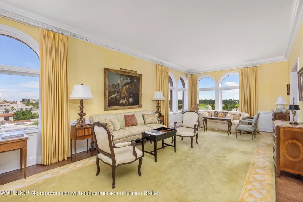 Depicted is a pale-yellow sitting room with antique wooden furniture,