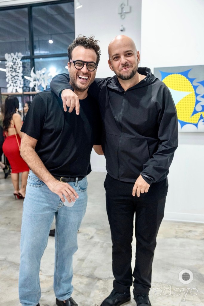 two artists pose together inside an art gallery