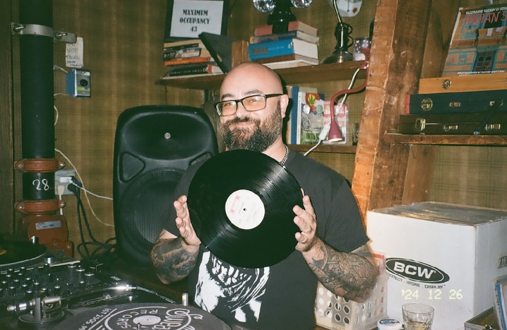 Picture of a man holding a record at a bar.