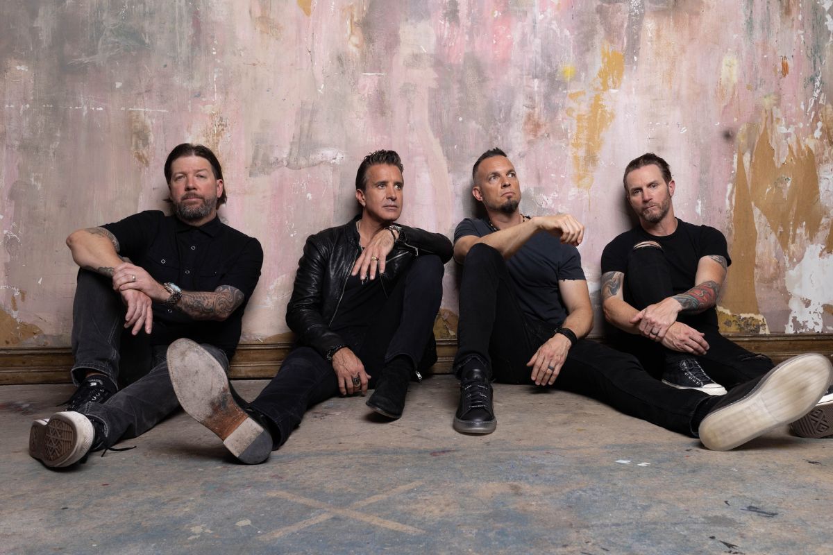 Picture of four men sitting by a wall.