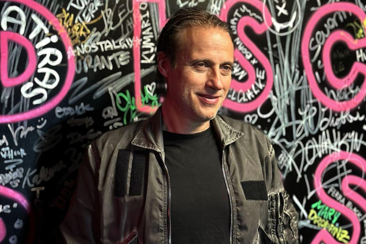 Picture of a man in front of a graffitied wall.