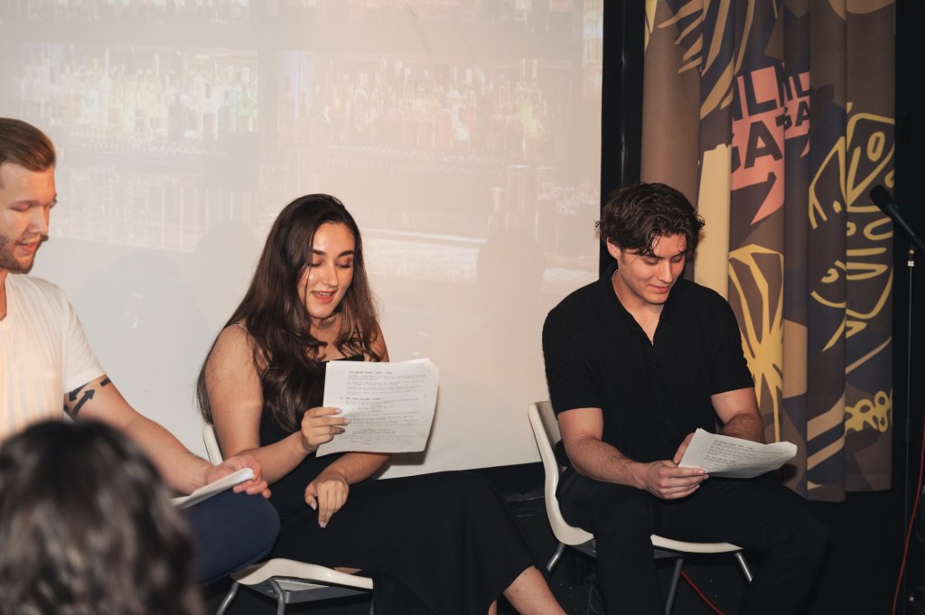 three actors read a script onstage during a live reading