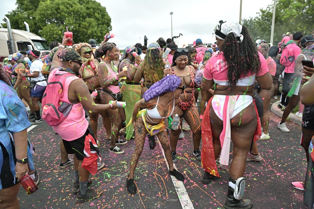 dozens of people dance and spray paint on each other at an outdoor festival