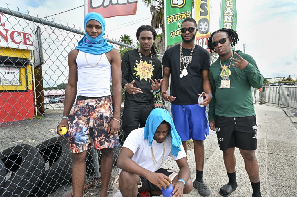 five young men pose by the chainlink fence outside a festival