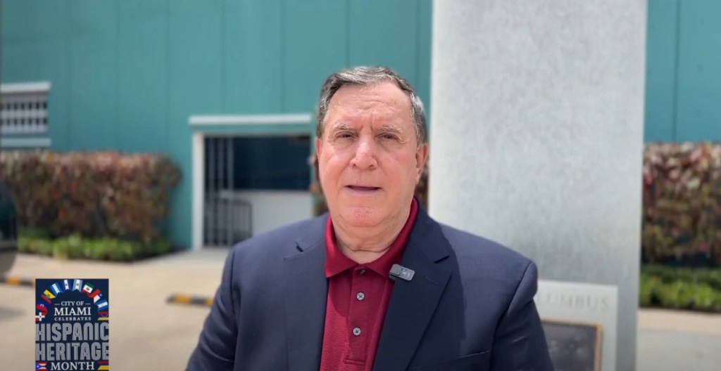 Joe Carollo looks into camera wearing navy sport jacket and red polo