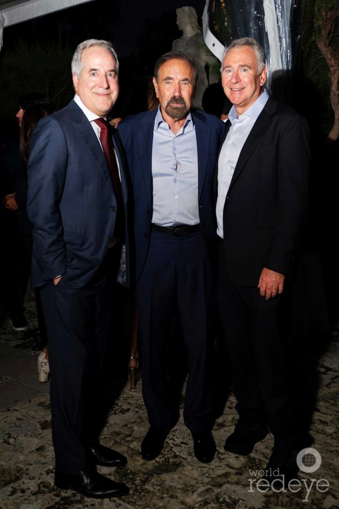 three men in suits pose together