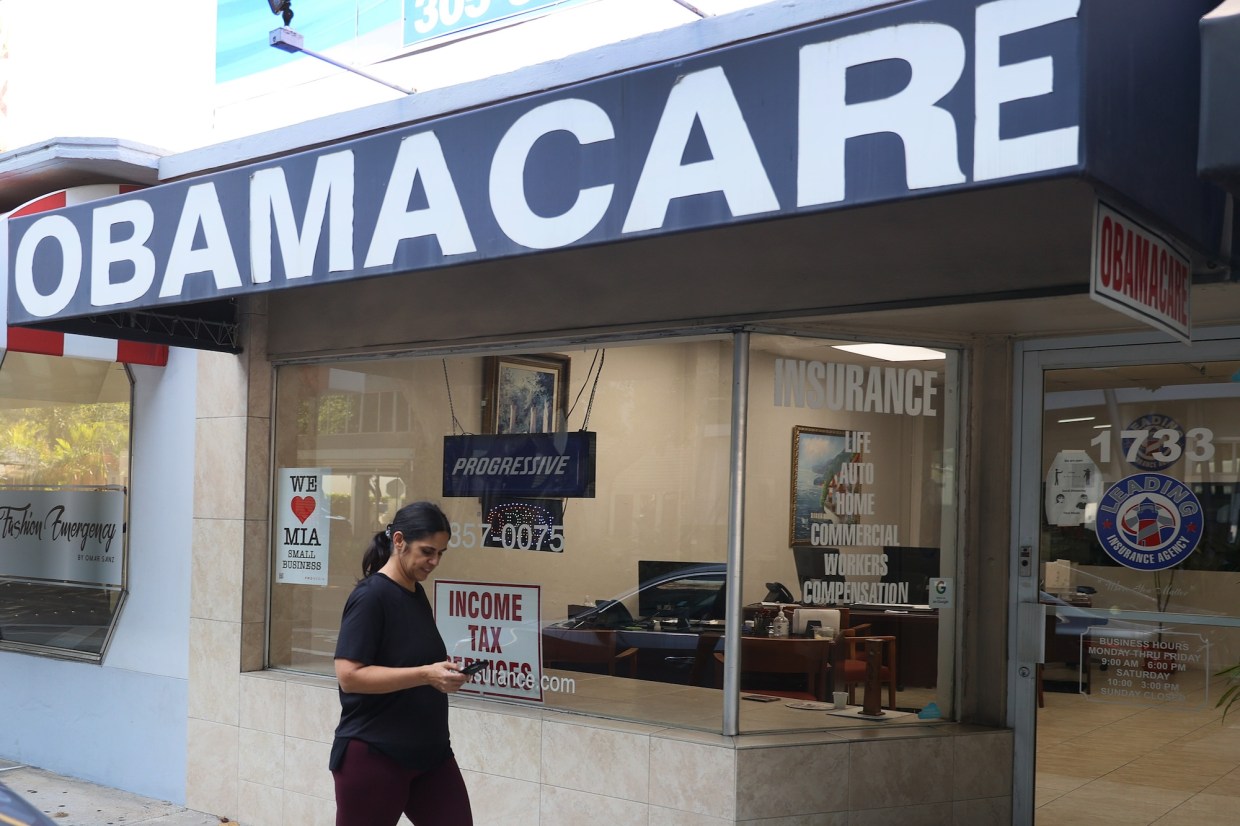 A pedestrian walks past the Leading Insurance Agency, which offers plans under the Affordable Care Act (also known as Obamacare) on Coral Way just west of Miami's Brickell neighborhood