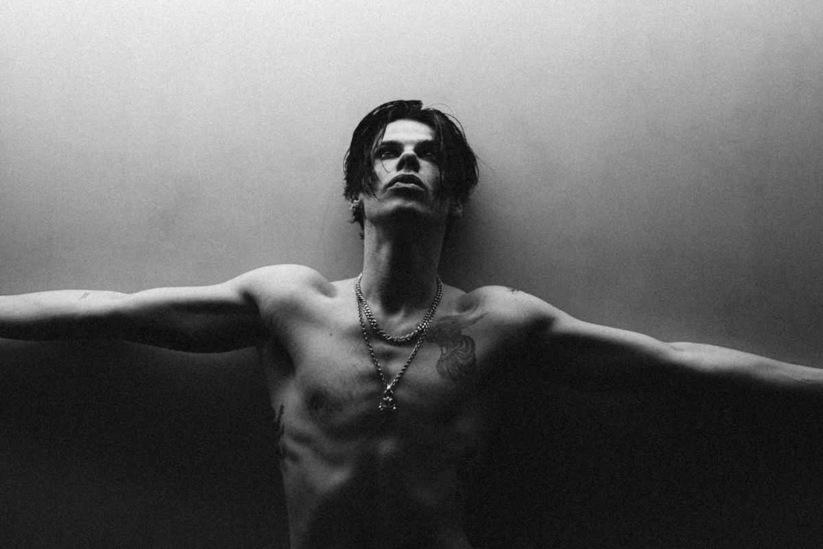 Black and white picture of a shirtless man with his arms open.