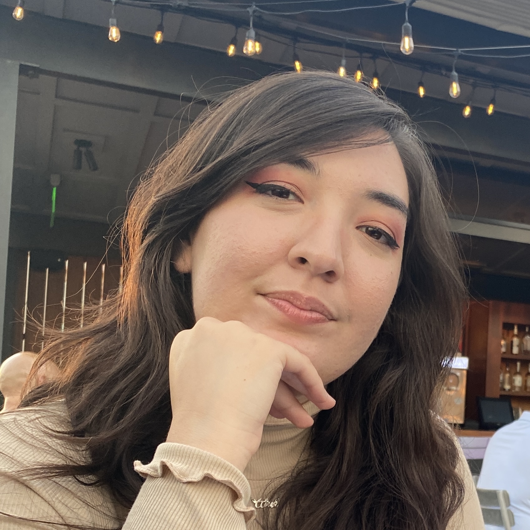 headshot of a woman with dark hair sitting at an outdoor dining establishement