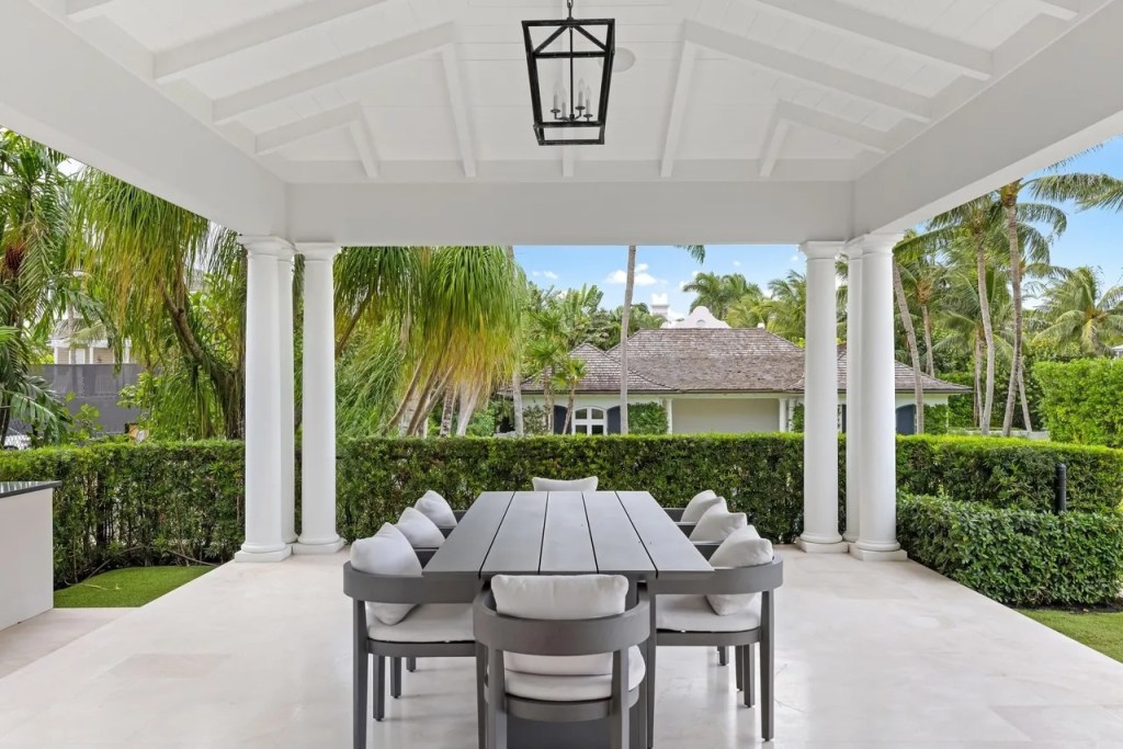 a dining table and eight chairs sit under a white awning in a backyard