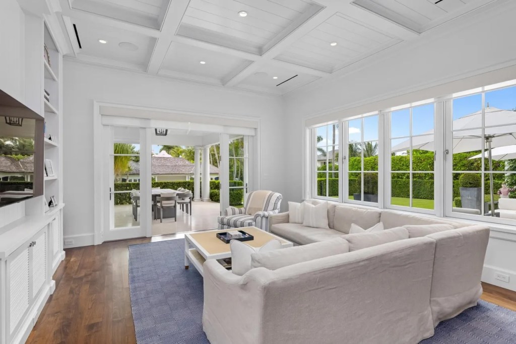 an L-shaped couch and arm chair rest on a blue rug in a sunlight-soaked sitting room