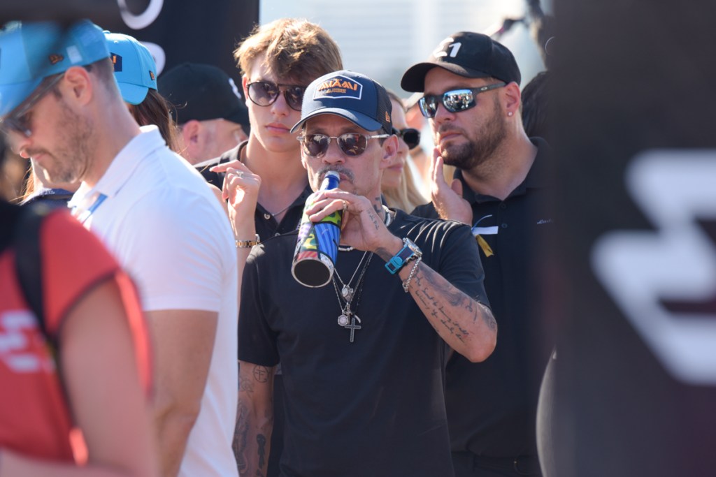 photo of Marc Anthony in a dark t-shirt and baseball cap standing in the middle of a crowd