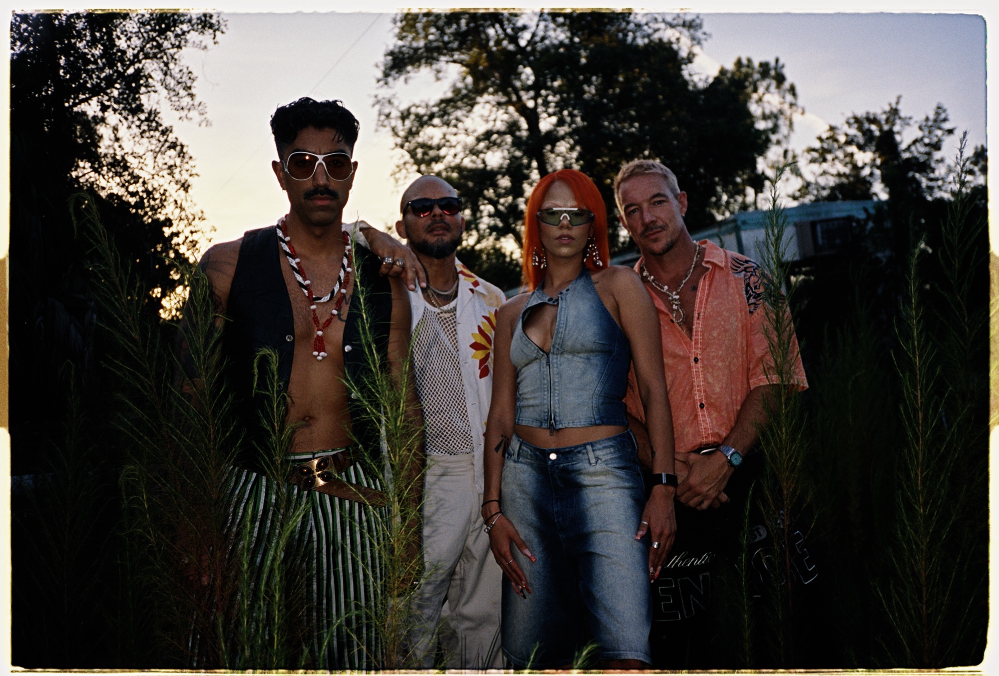 A group of four people posing for the camera in between trees.