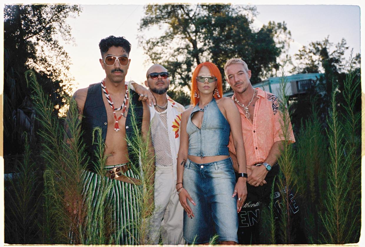 A group of four people posing for the camera in between trees.