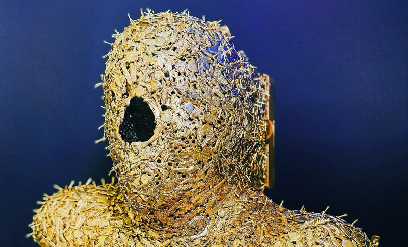 photo of a mask with a hole in the center covered in gold broaches