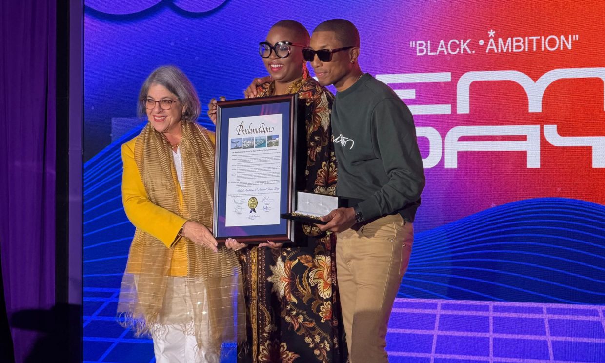 Photo of three people holding a frame.