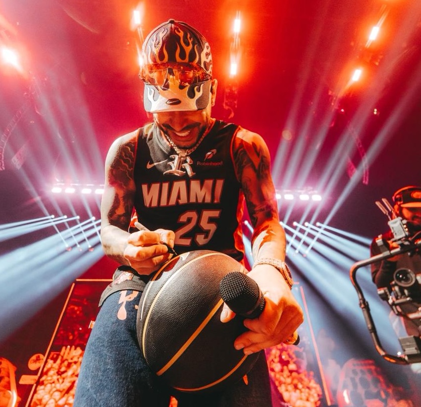 Photo of Ryan Castro wearing a Miami Heat jersey and signing a basketball.