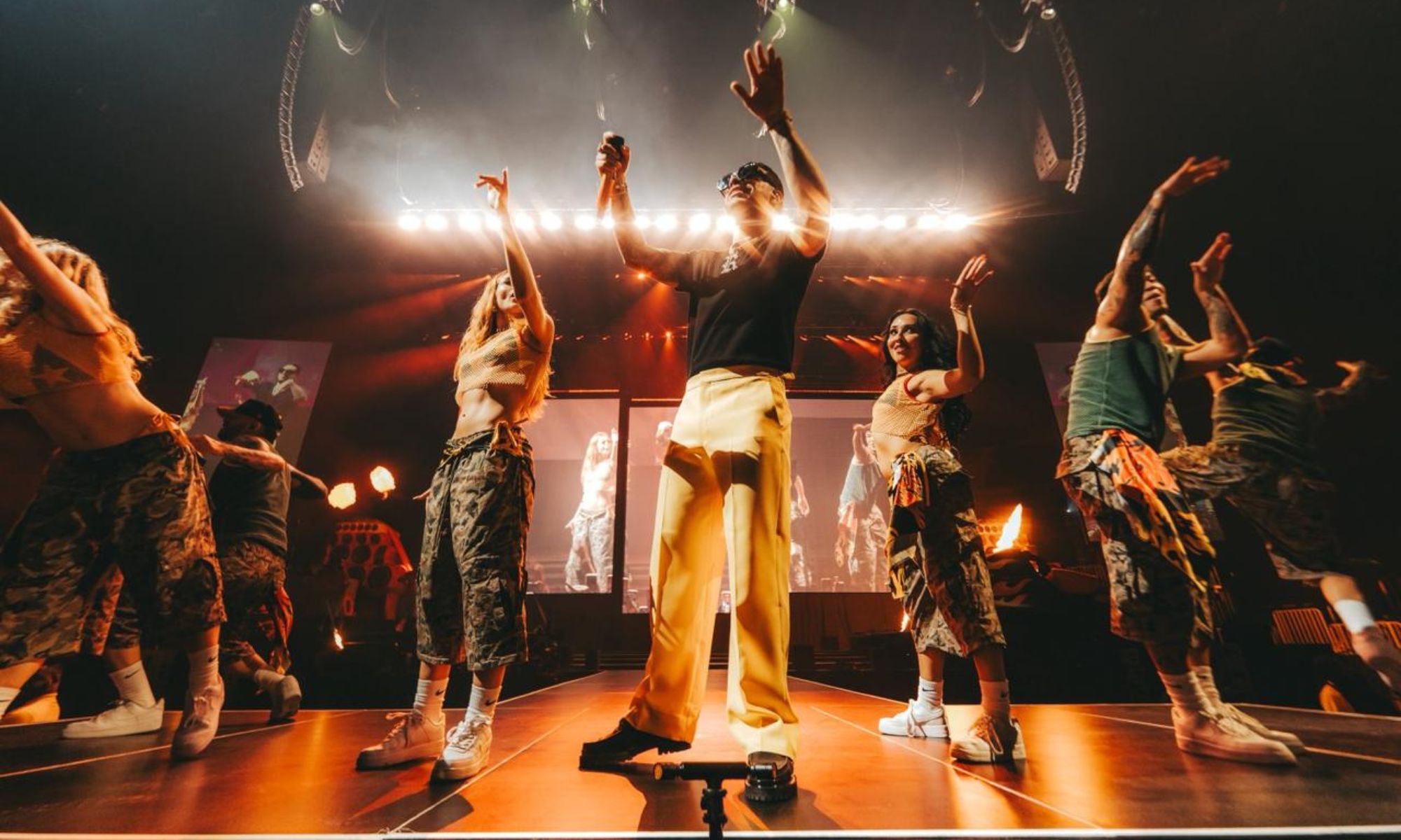 Photo of a singer on stage surrounded by dancers.