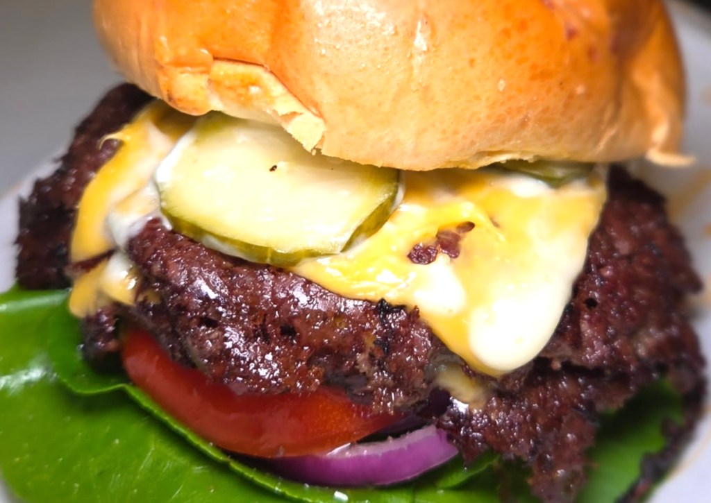 a cheeseburger with toppings and tomato 