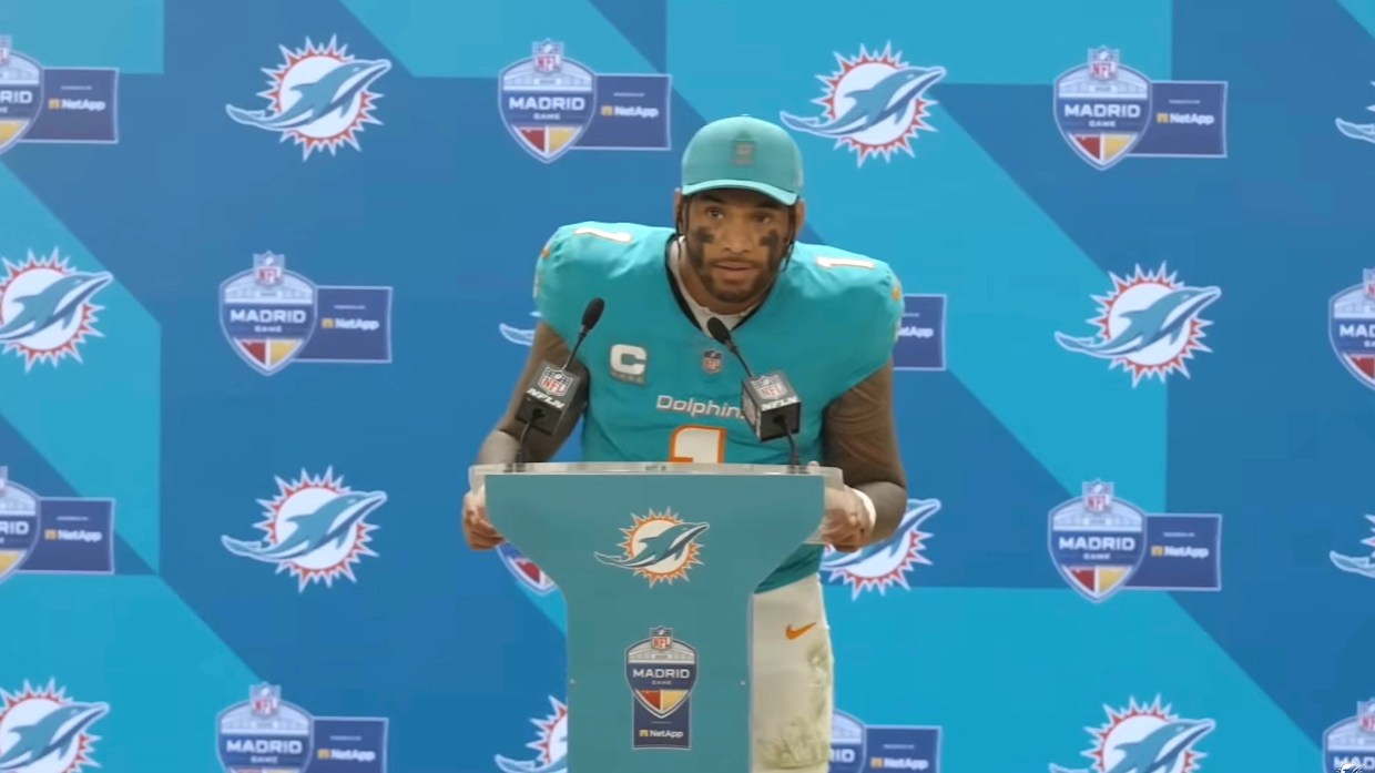 Miami Dolphins quarterback in uniform and speaking into microphone at press conference podium
