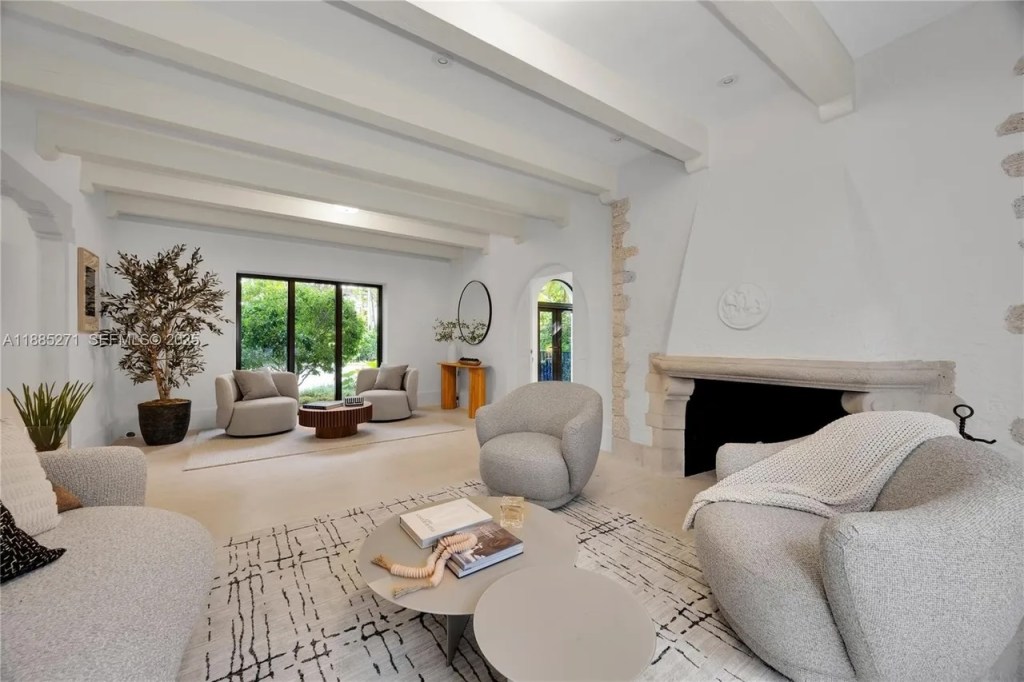 a modern-inspired living room is shown with a fireplace accompanied by tan-colored couches and arm chairs