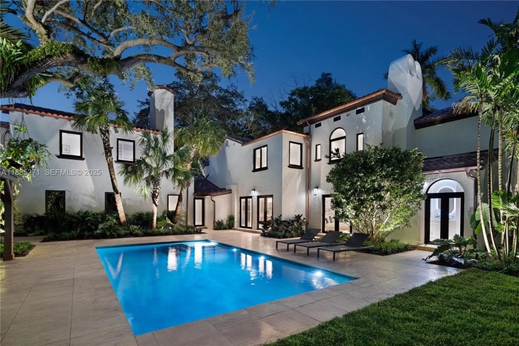 a resort-style pool is shown in the foreground, surrounded by a Mediterranean-inspired mansion with wide windows looking over the pool area