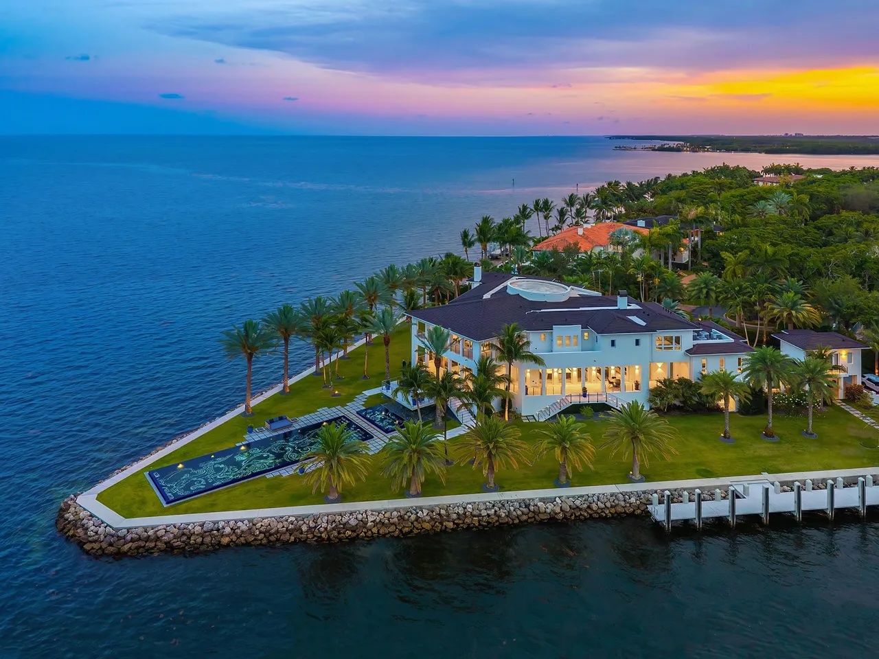 a massive mansion sits on an estate surrounded by blue water