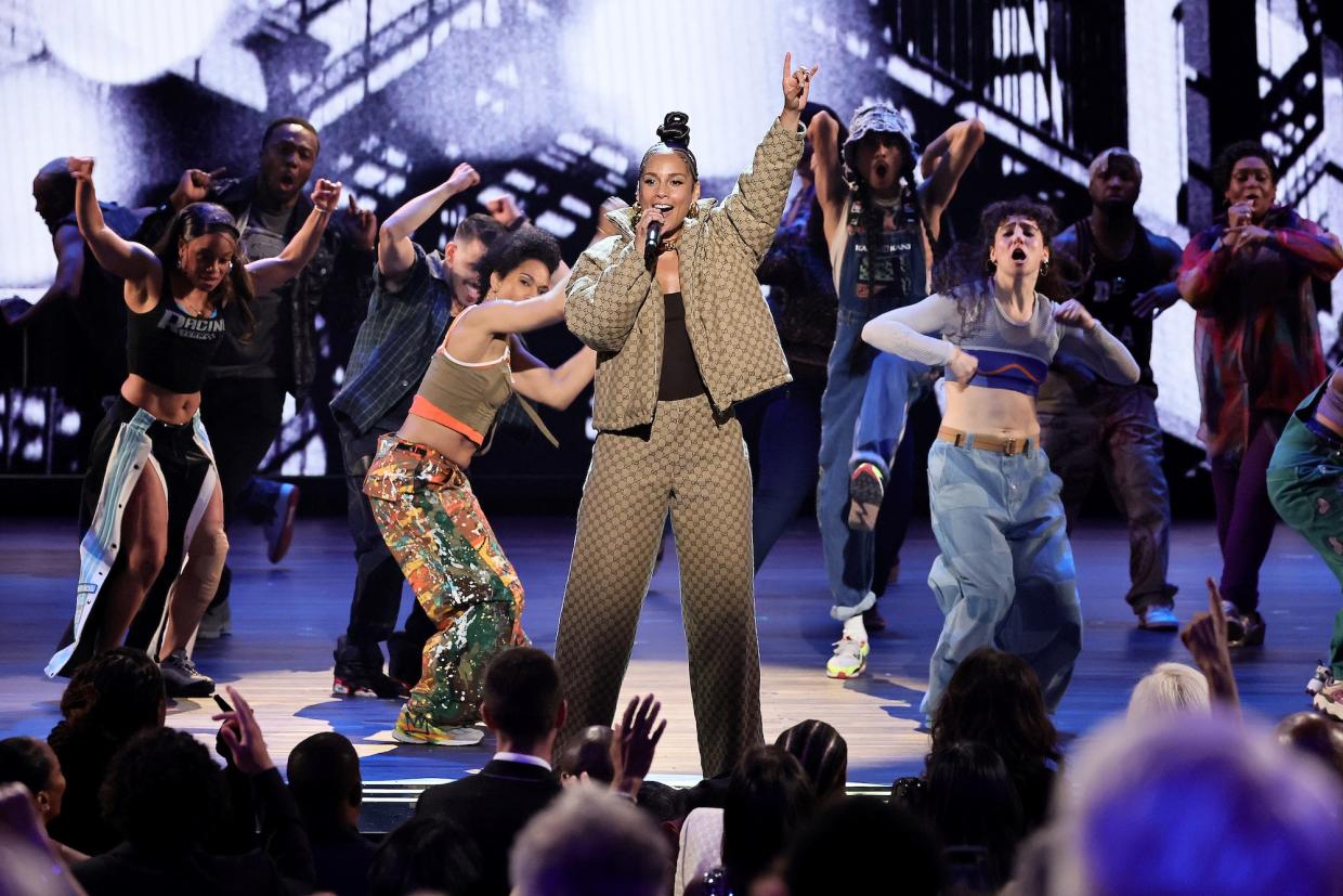 A woman singing on stage surrounded by dancers.