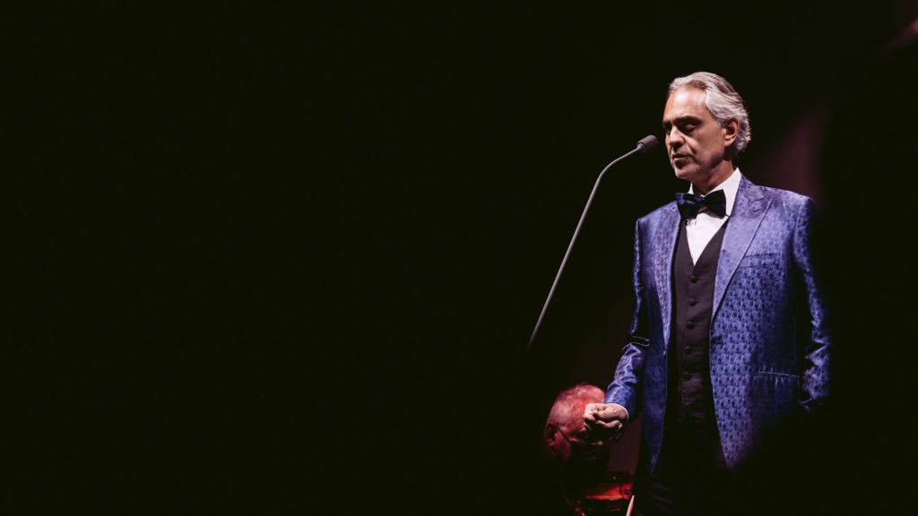 Photo of a man on stage wearing a blue smoking 