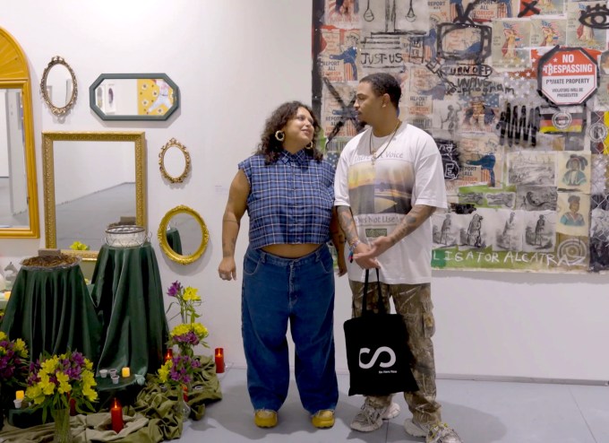 photo of two artists looking at each other between their two installations inside a gallery