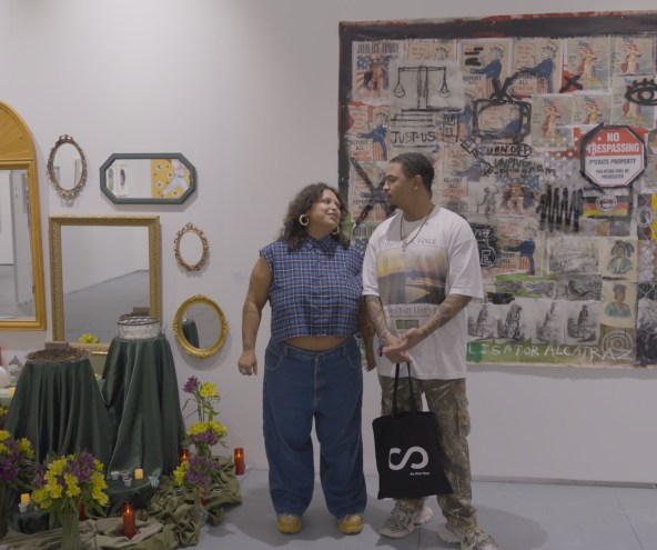 photo of two artists looking at each other between their two installations inside a gallery