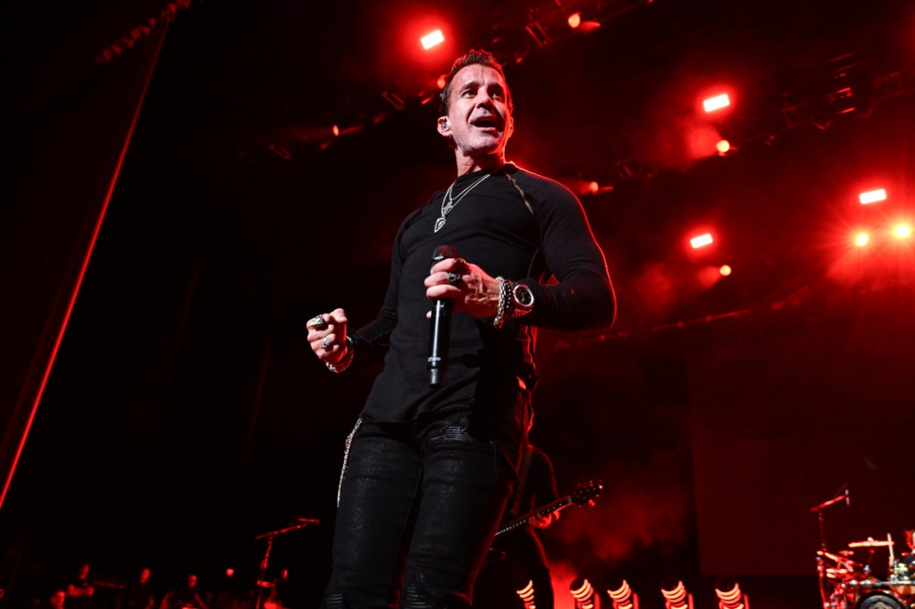 Creed's singer Scott Stapp on stage holding a microphone.