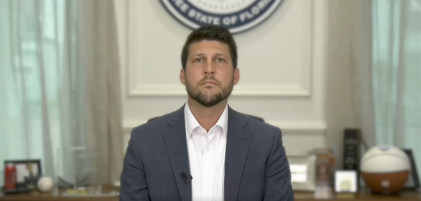 Florida Attorney General James Uthmeier speaks from his desk, donning a grey blazer and white shirt