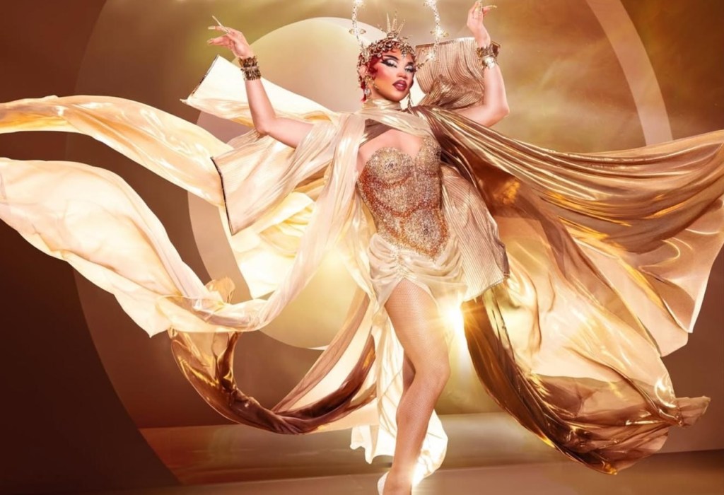 photo of a drag performer in a rhinestoned corset with draped silk and a crown