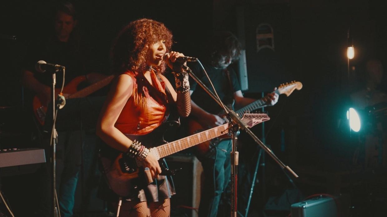 Photo of a young woman on stage playing guitar.