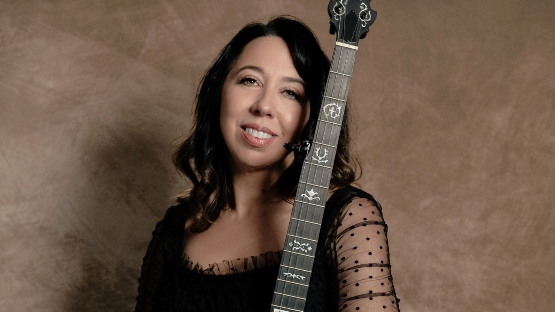 A photo of woman holdin a banjo