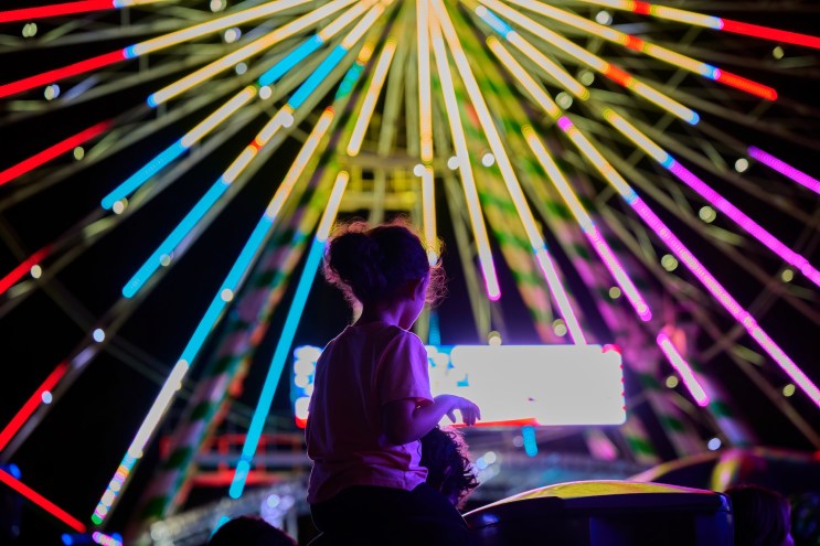 photo of the silhouette of a child in front of a ferris wheel