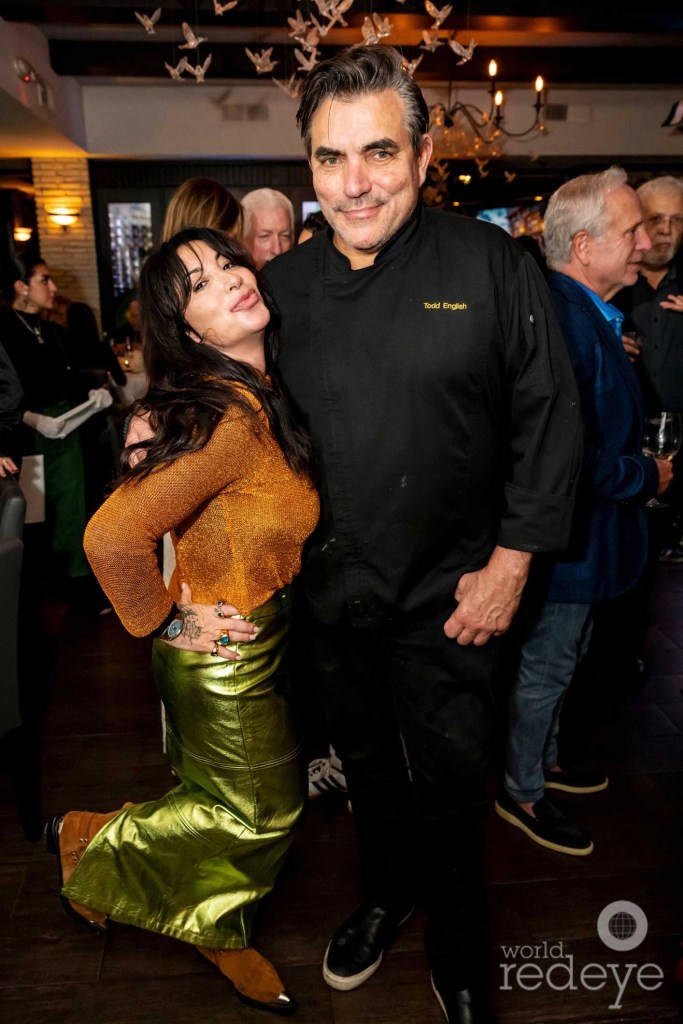 photo of a woman posing with a chef in a black uniform at a party