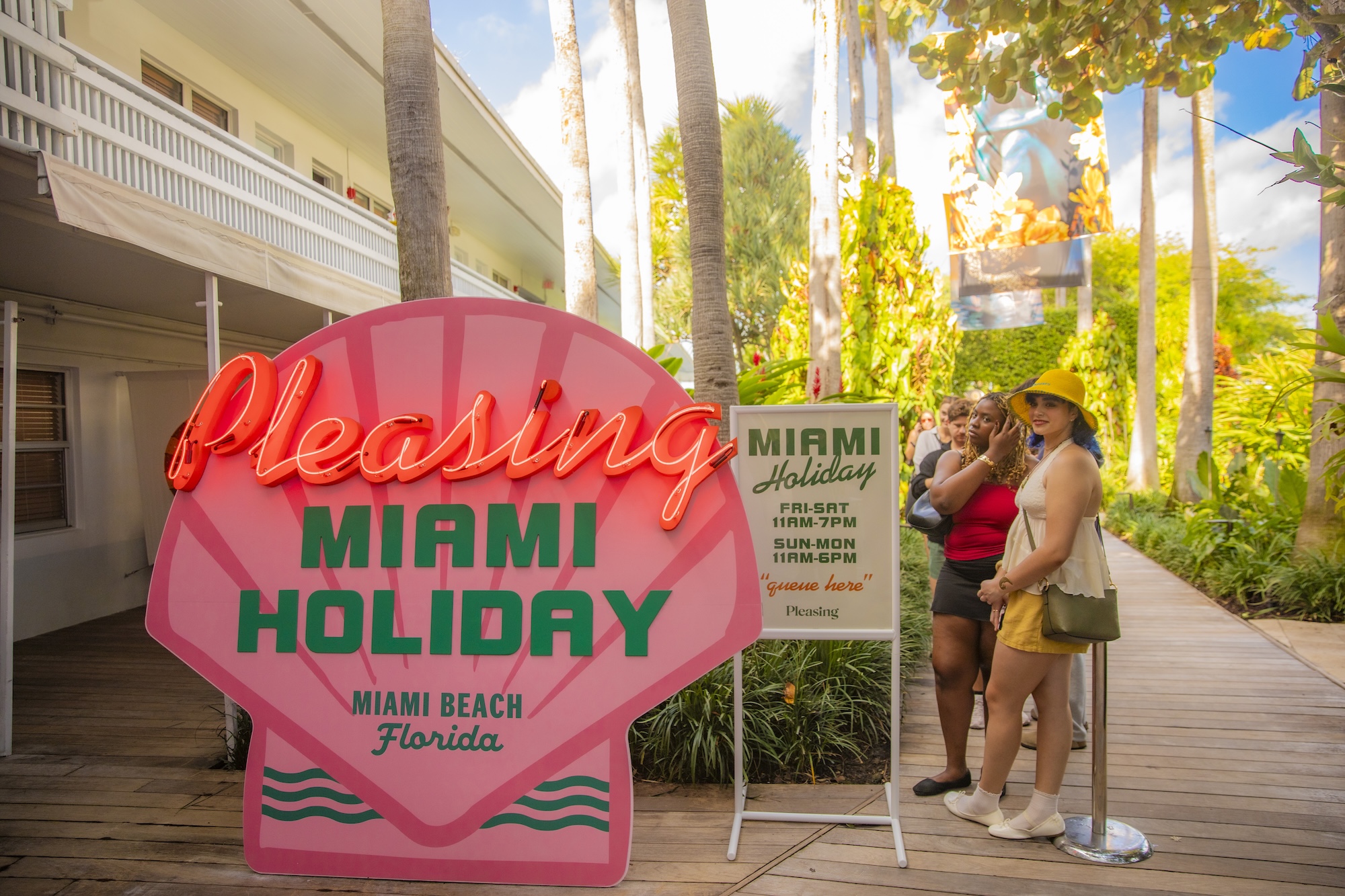 photo of a wooden sign of a sign painted like a pink seashell reading "Pleasing Miami Holiday, Miami Beach Florida"