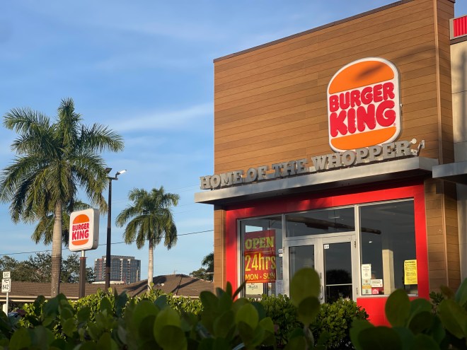 A Burger King store is surrounded by palm trees and South Florida shrubs