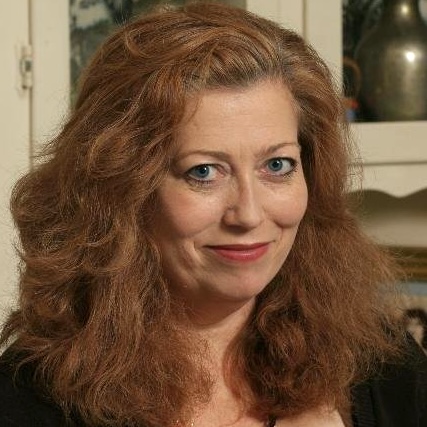 headshot of a smiling woman with blue eyes and flowing red hair