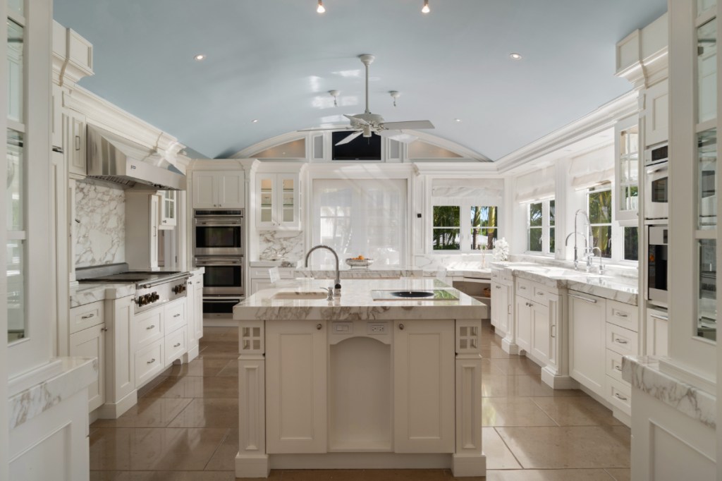 An elegant kitchen with white cabinets, marble countertops and an island