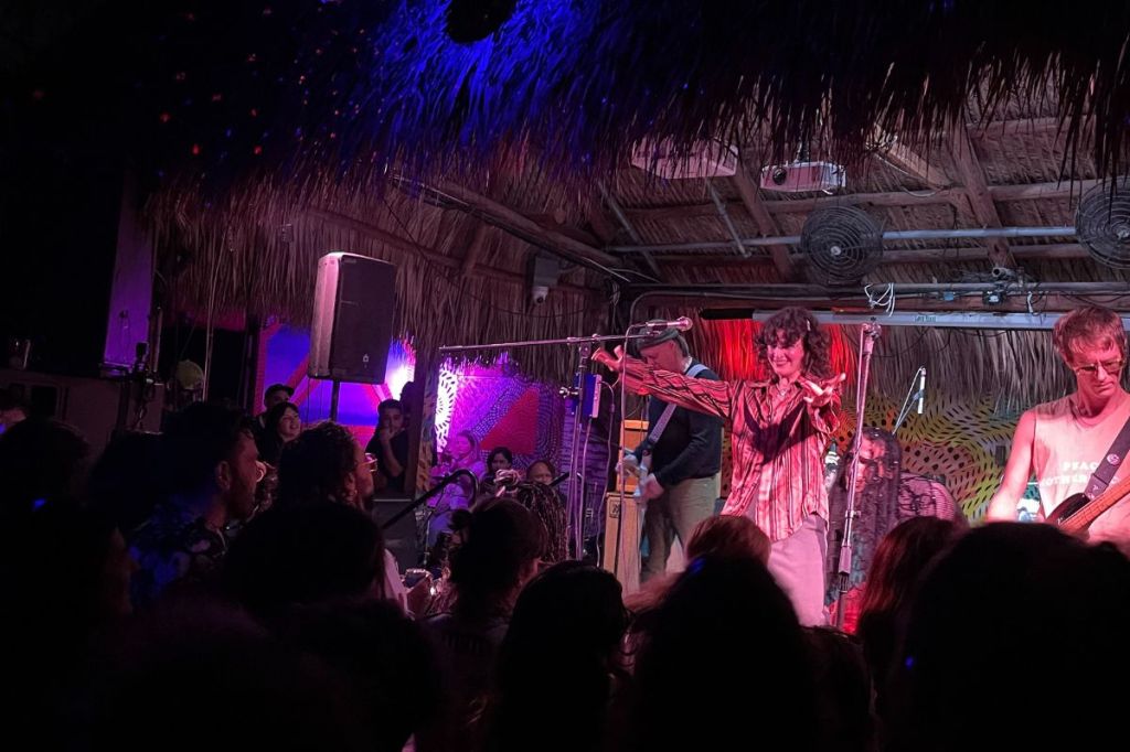 A photo of a band on stage under purple lights