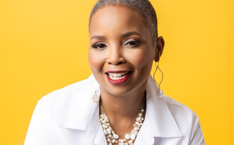 professional headshot of a woman in a white button-down in front of a bright yellow backdrop
