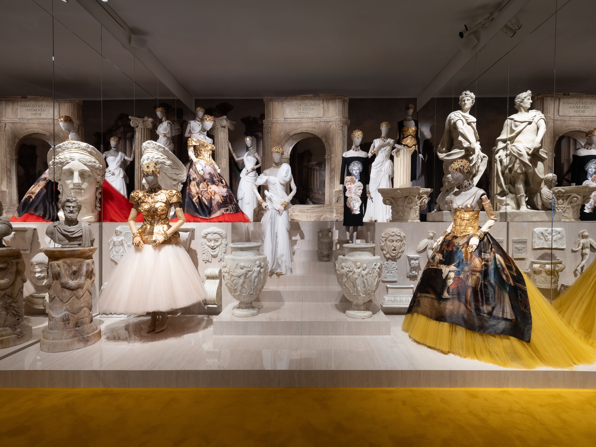 photo of ornate dresses on mannequins on a platform inside an art gallery