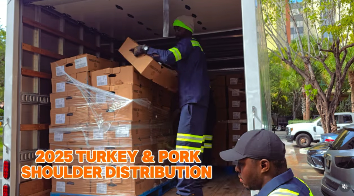 Two men emptying a U-Haul filled with boxes of pork shoulder