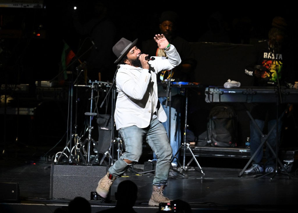 a man singing on stage wearing a white jacket